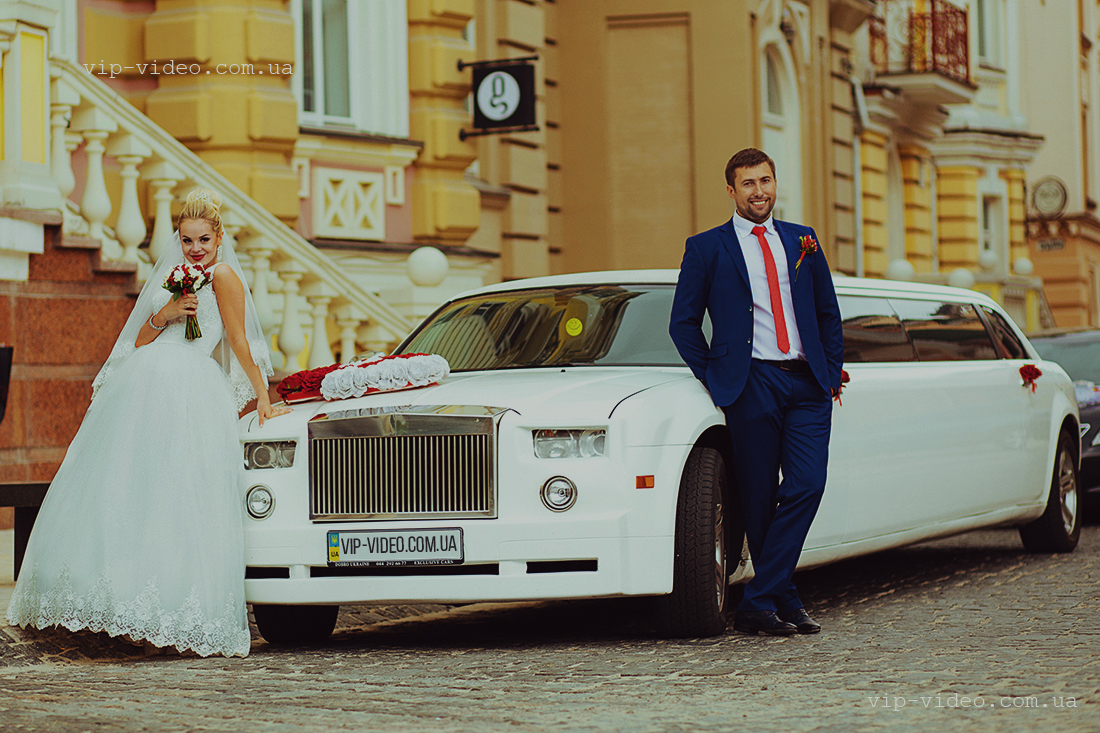 Фотографія на котрій наречена і наречений стоять по обидві бока білого лімузіна