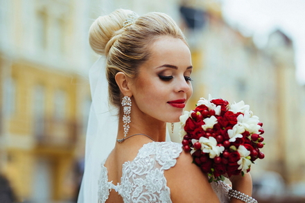 Фотографія нареченої з весільним букетов на фоні будинків міста